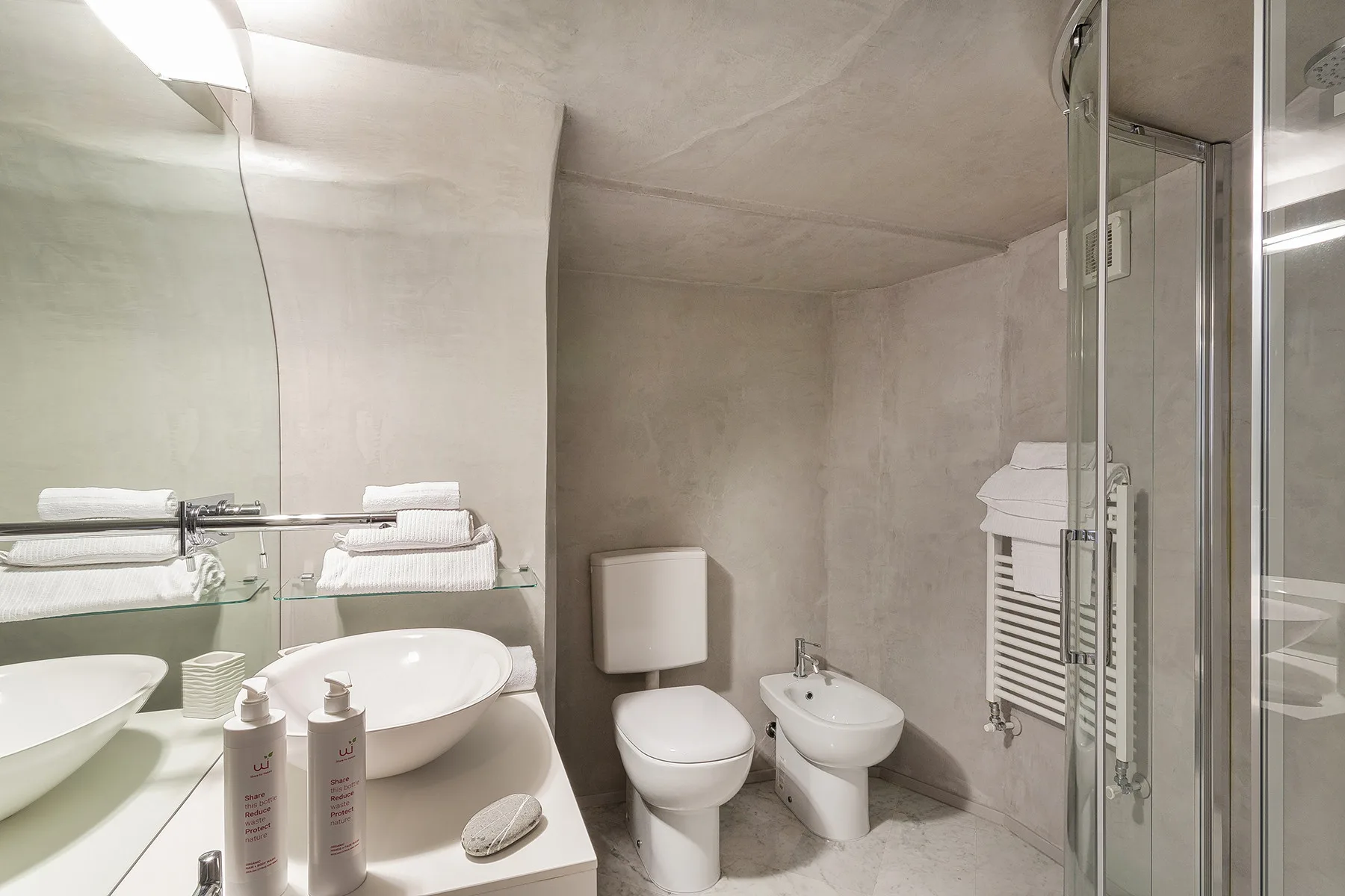 Un baño con inodoro, bidé, lavabo y ducha de vidrio.
