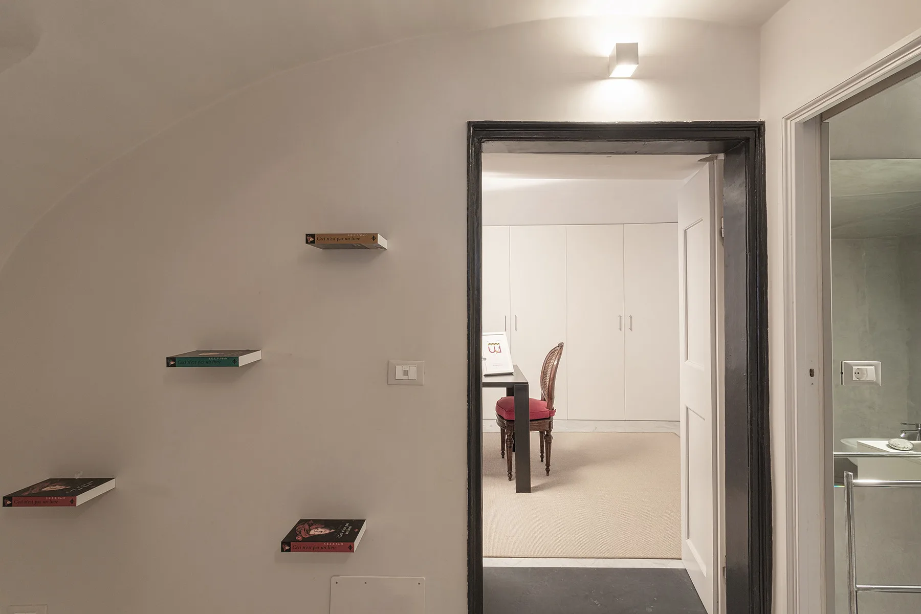 Un pasillo da a una habitación luminosa con escritorio y silla.