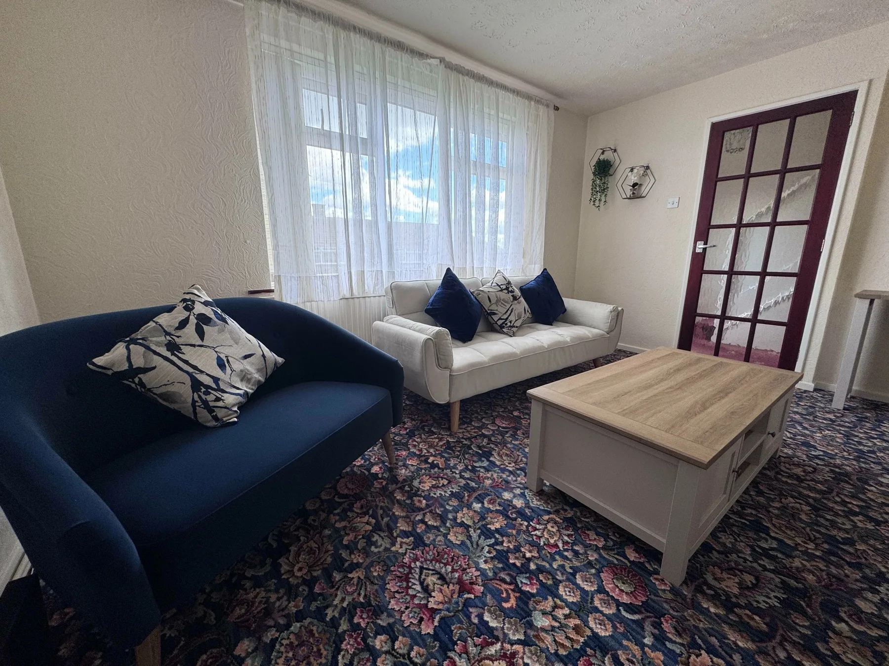 Una sala de estar con dos sofás, una mesa de centro y una alfombra estampada.