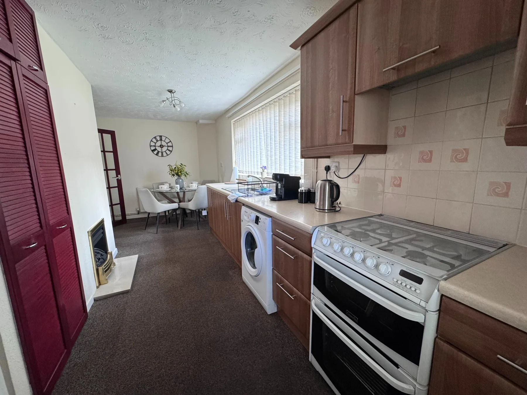 A kitchen with wood cabinets and a dining table at the far end.