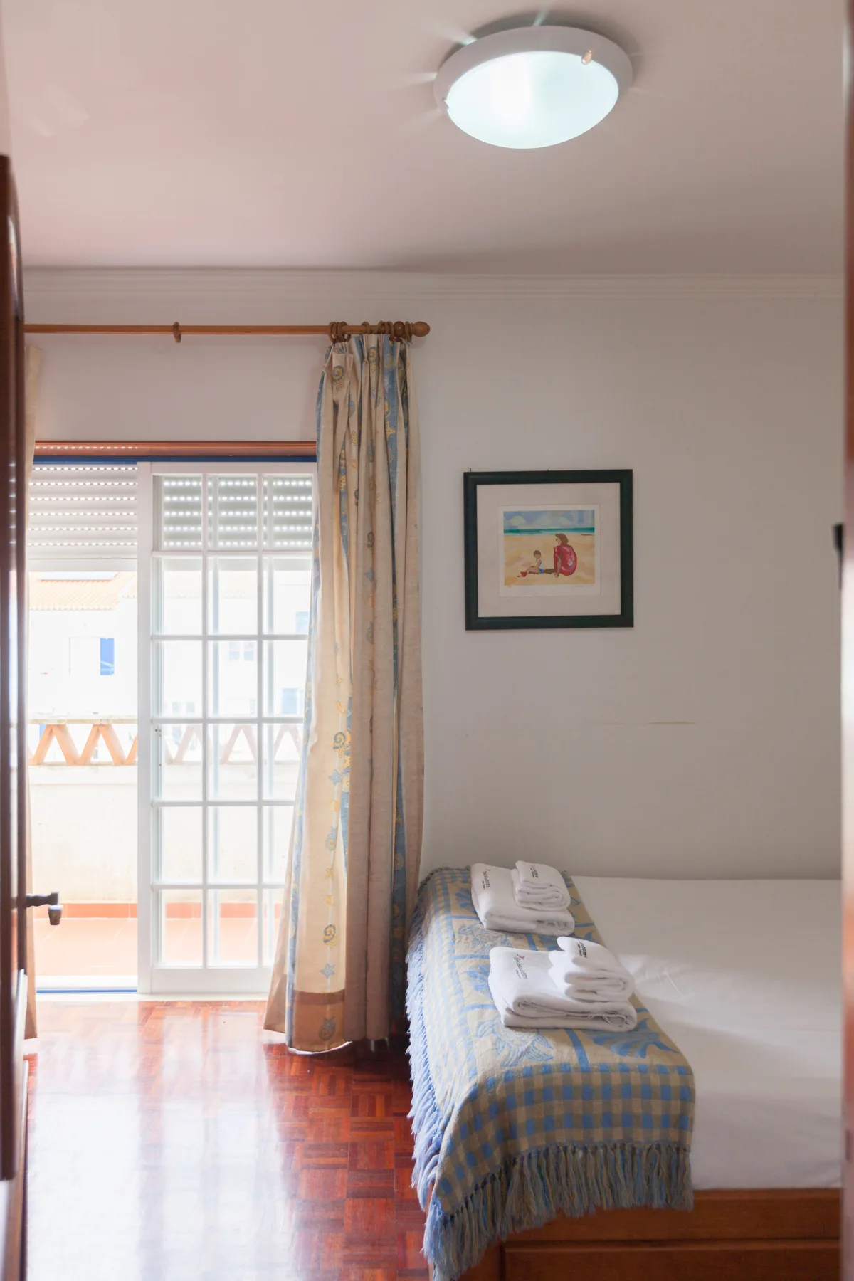 A bedroom with a bed beside a window and balcony doors.