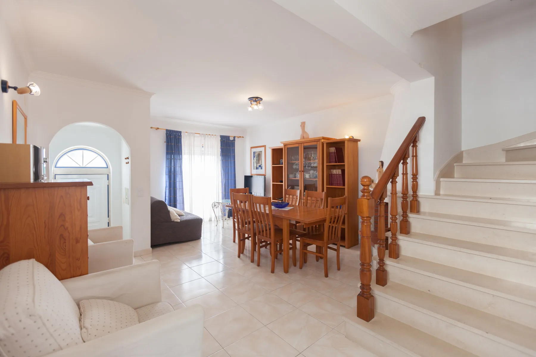 A living and dining area with a wooden table beside a staircase.