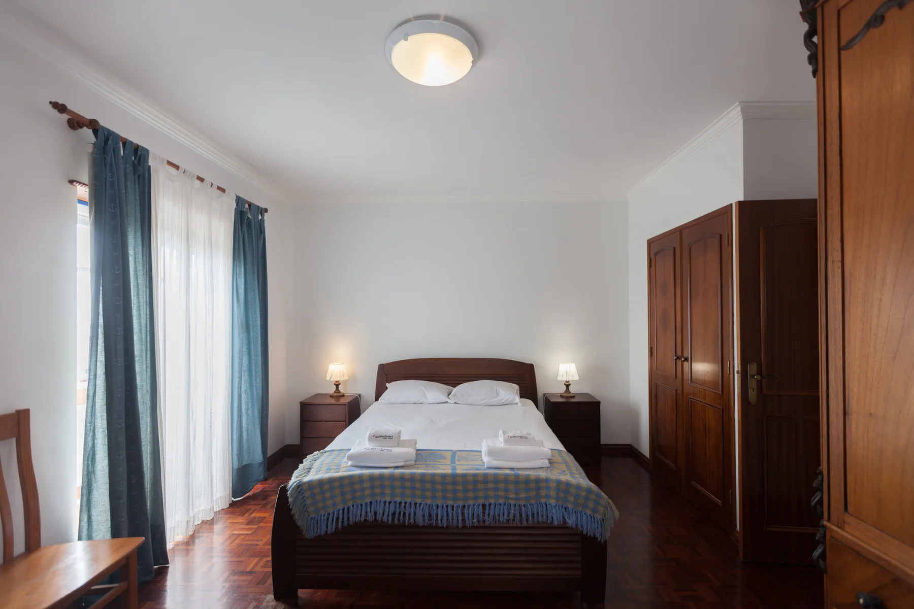 Bedroom with a double bed, bedside tables, and blue curtains.