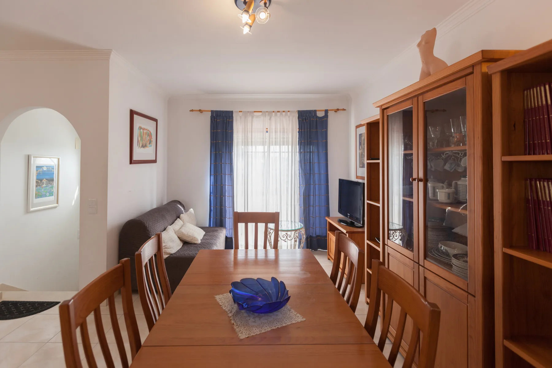 A dining room with a wooden table and chairs beside a living area.