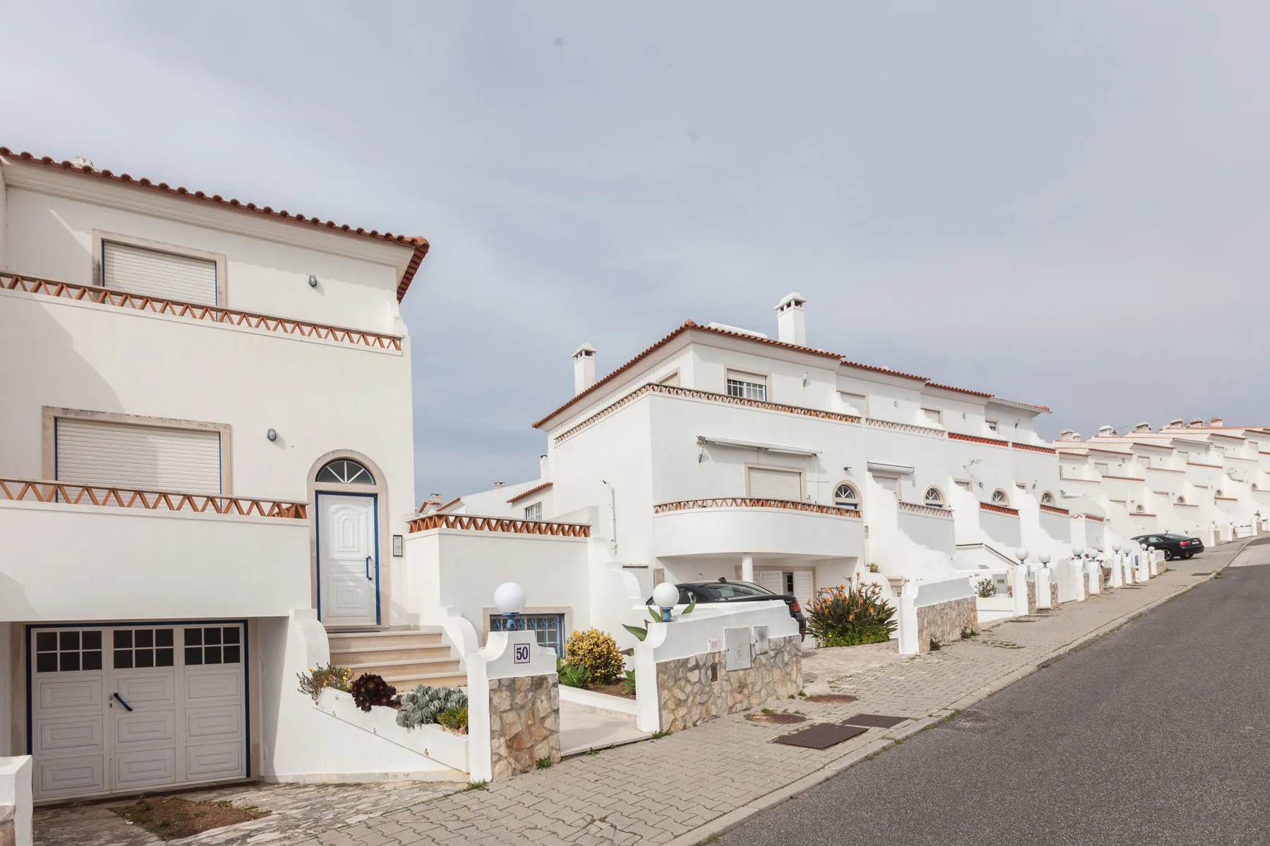 A row of white houses lines a paved street under an overcast sky.