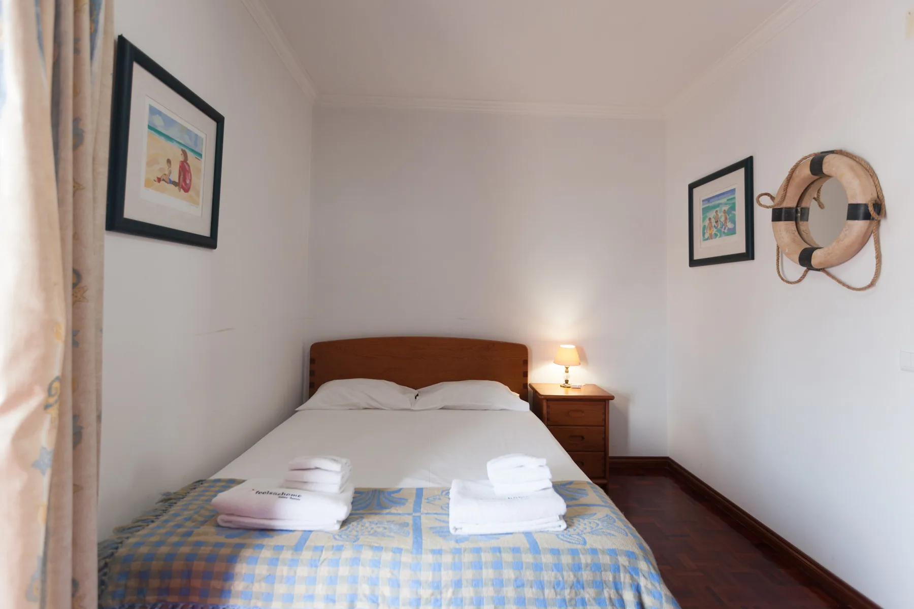 Un dormitorio con la cama tendida y cuadros en las paredes.