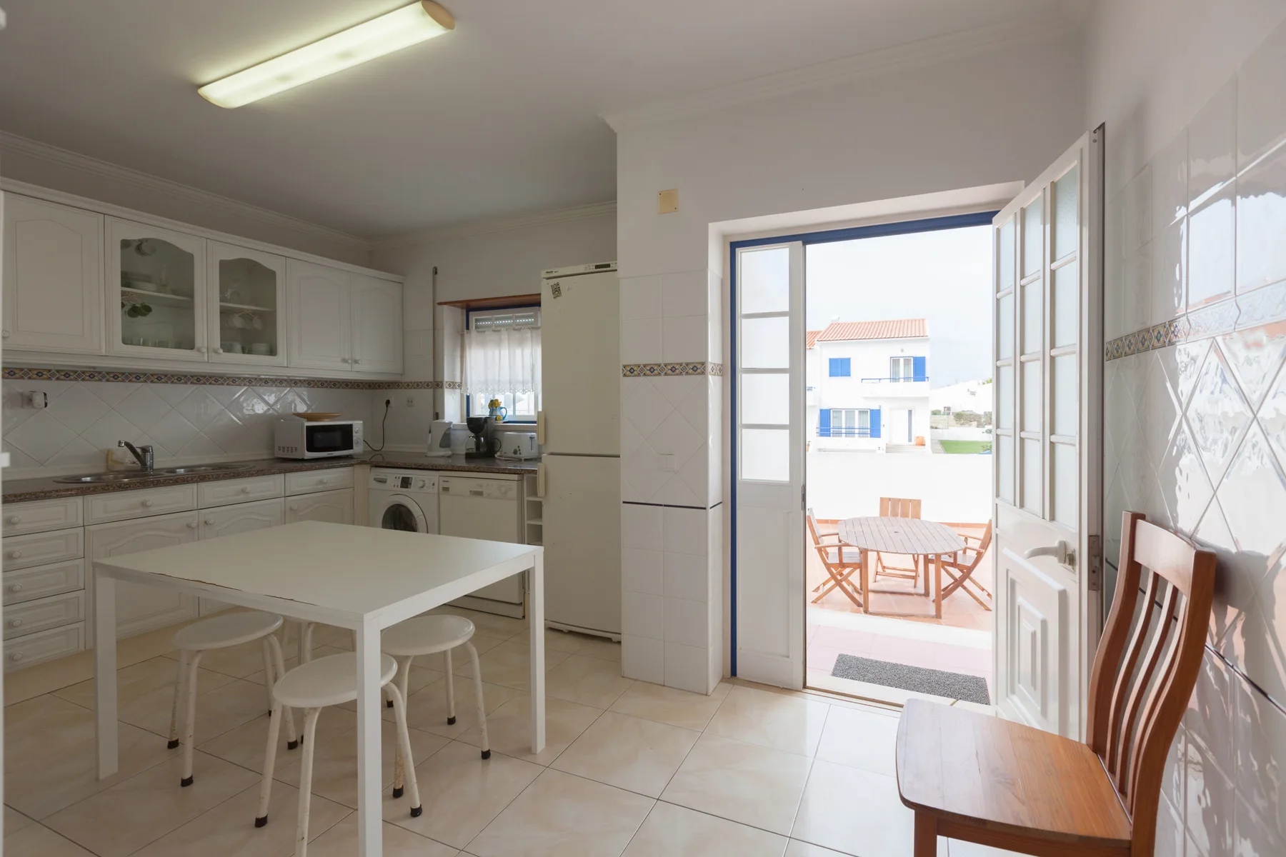 A kitchen and dining area opens onto a terrace through an open doorway.