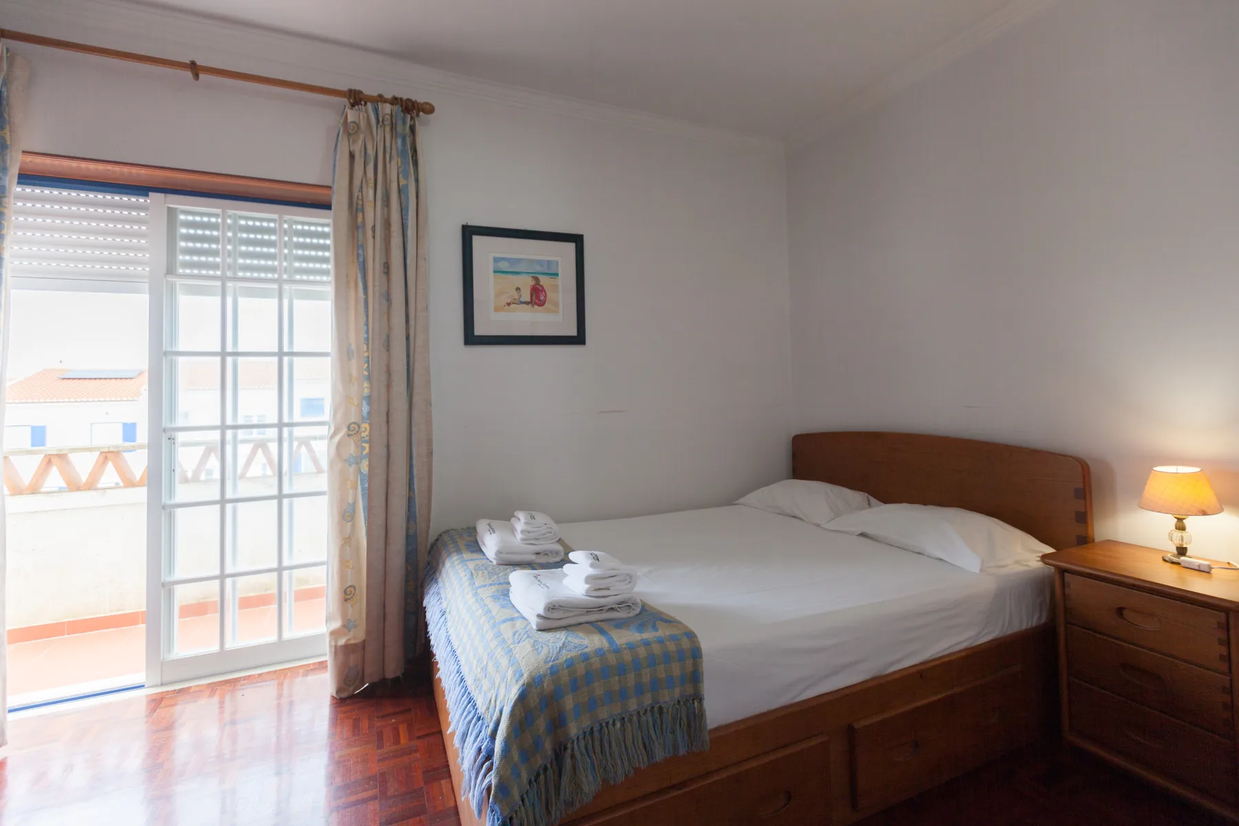 A bedroom with a bed beside glass doors opening onto a balcony.