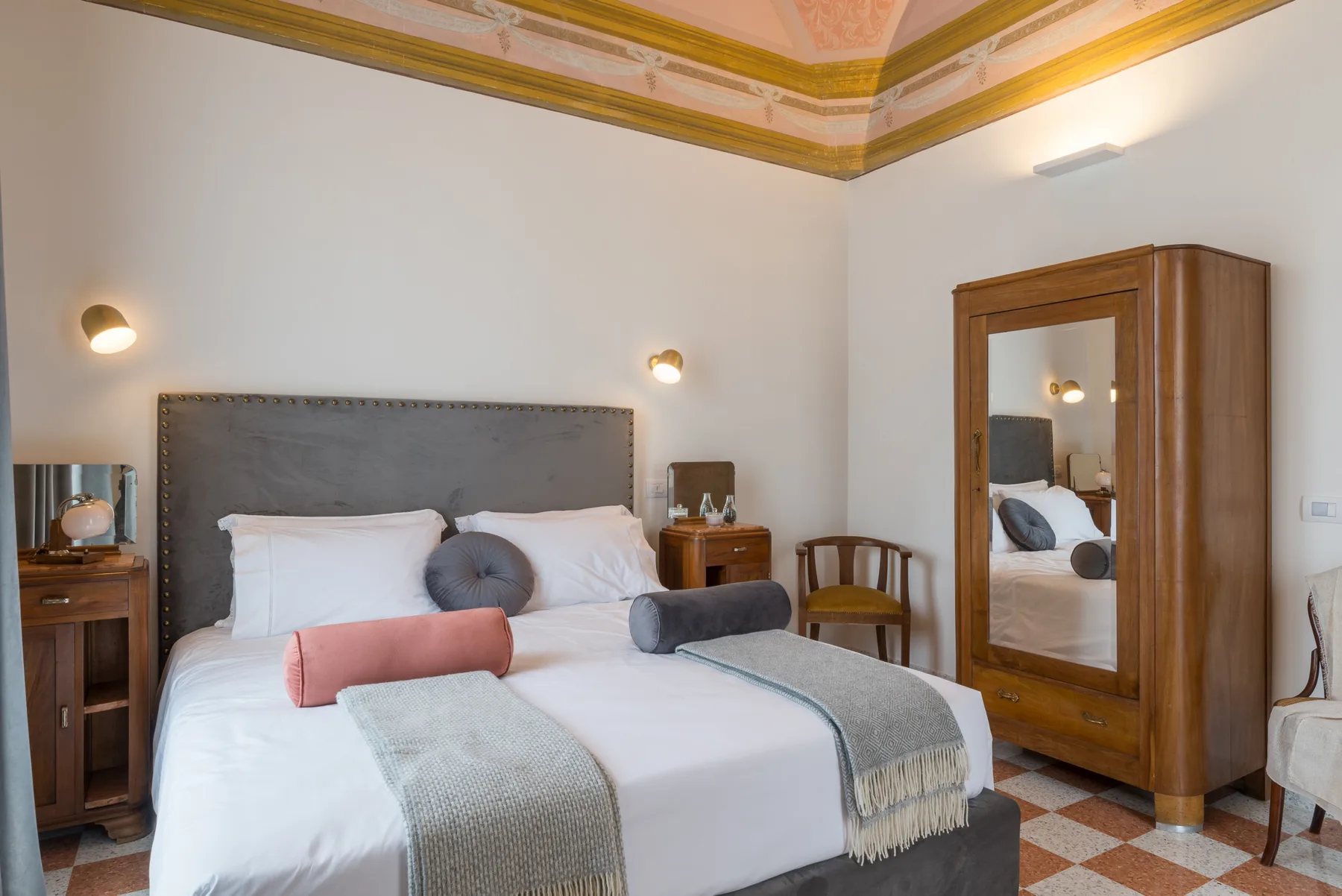 A bedroom with a neatly made bed and a wooden wardrobe.