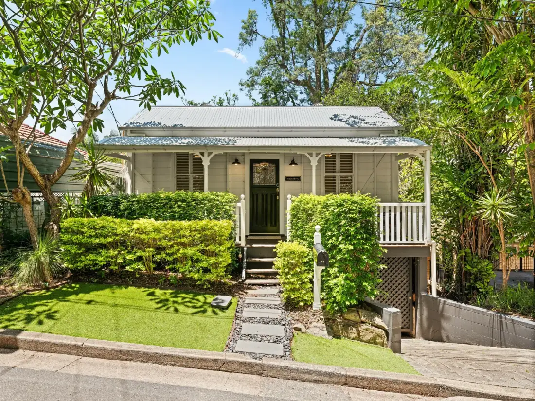 A small house stands behind a neat front garden and stone path.