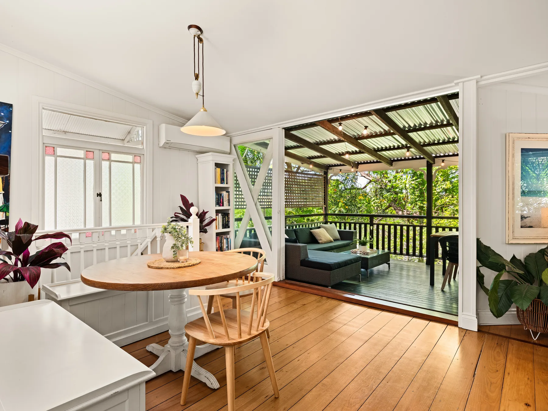 A dining area opens onto a covered outdoor seating space with garden views.