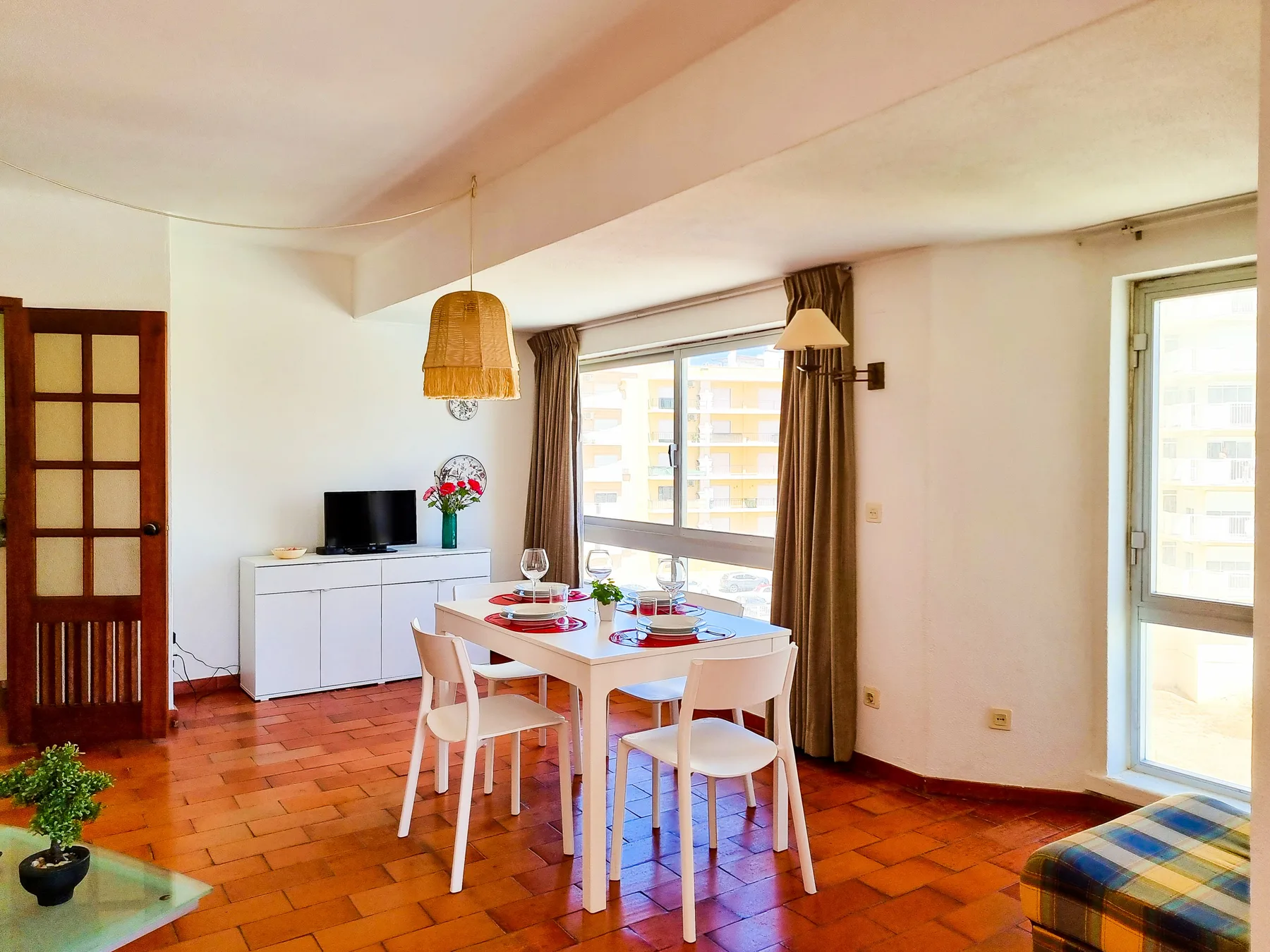 Un comedor con mesa y sillas está junto a grandes ventanas.