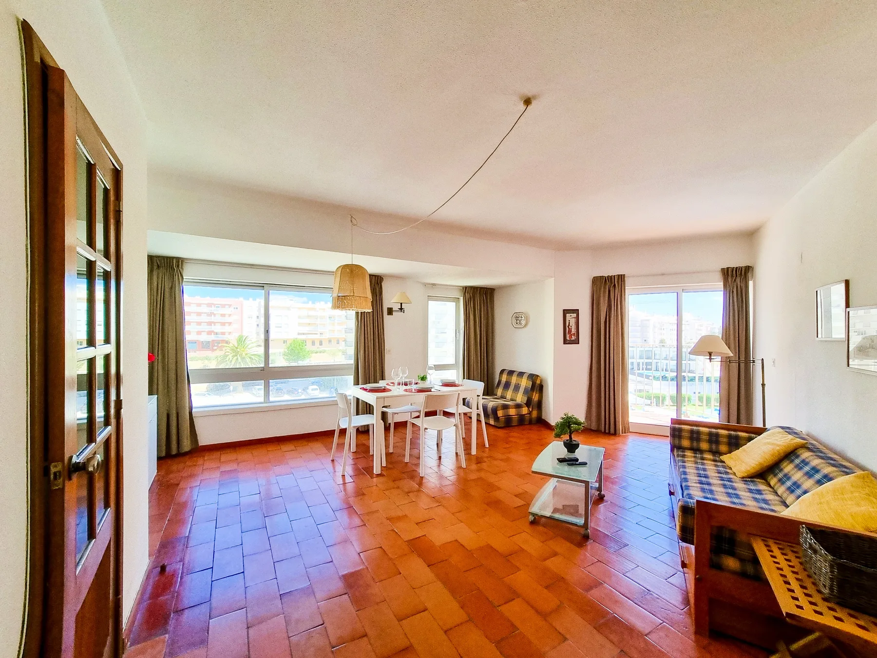 Una luminosa sala de estar y comedor con asientos junto a grandes ventanas.