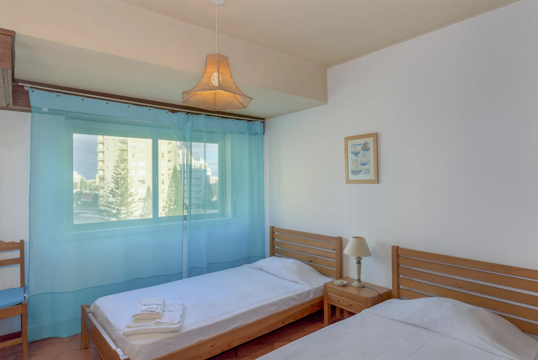 Un dormitorio con dos camas, cortinas azules y una pequeña mesa de noche.