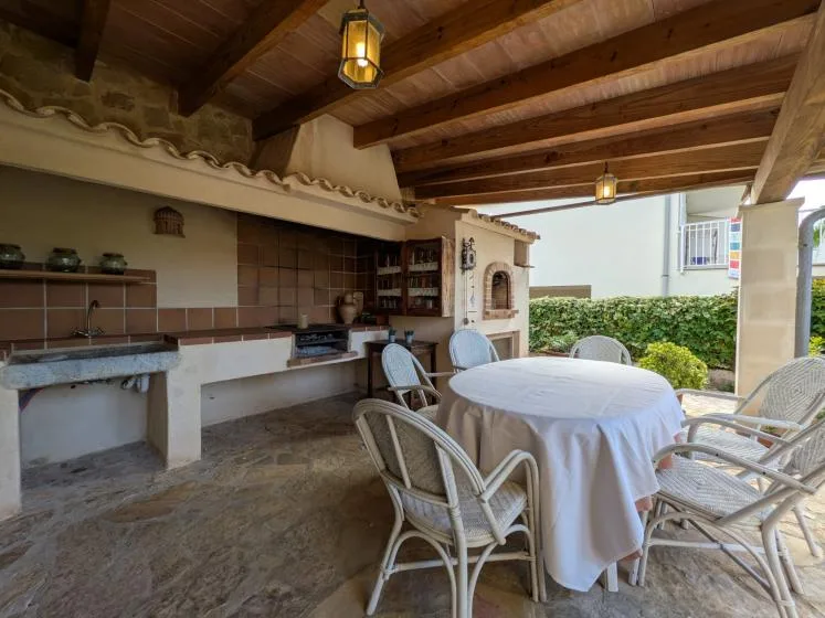 Covered outdoor dining area with a round table and built-in cooking counter.