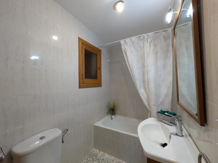 Un baño alicatado con bañera, lavabo y cortina de ducha.