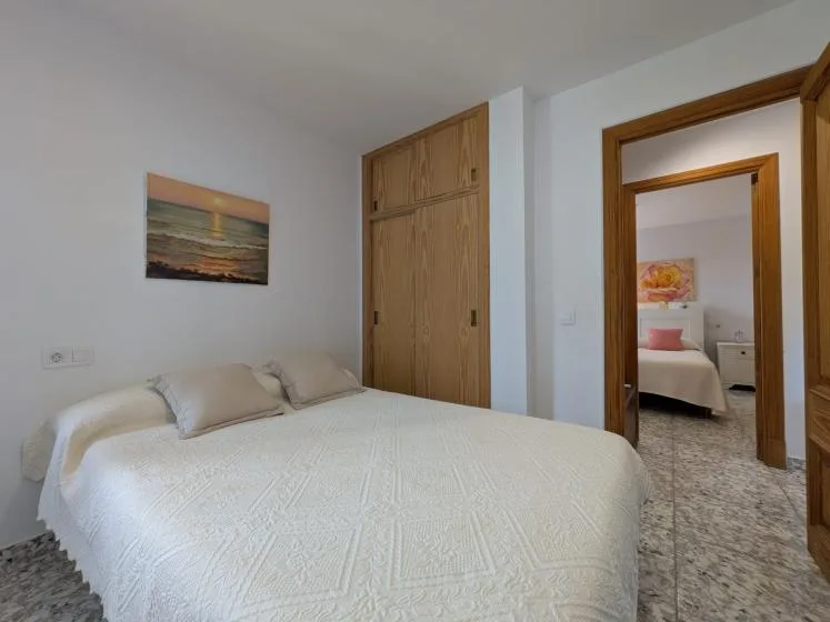 Un dormitorio con una cama grande, armarios de madera y una puerta hacia otra habitación.