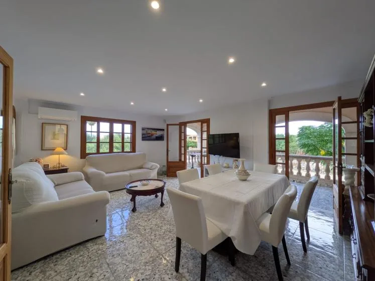 Una luminosa sala de estar y comedor con asientos, una mesa y ventanas amplias.