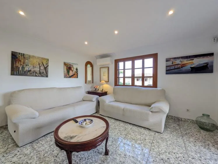 Una sala luminosa con asientos, una mesa de centro y cuadros en las paredes.