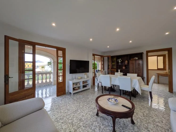 Una luminosa sala de estar y comedor tiene un televisor, una mesa y asientos.