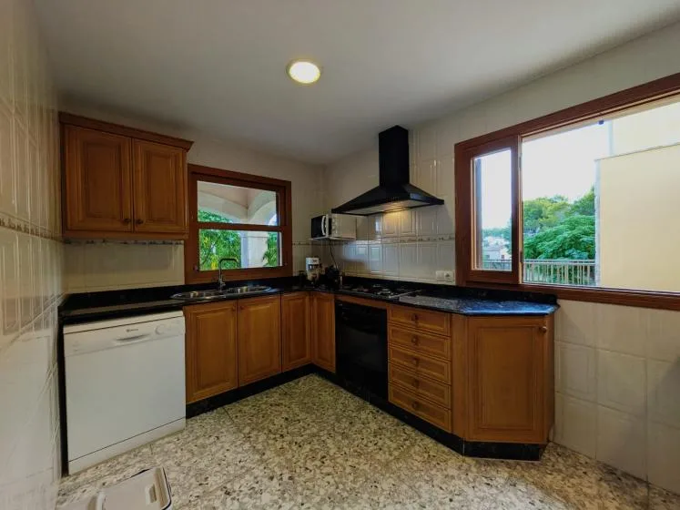 Una cocina con gabinetes de madera, encimeras oscuras y una ventana grande.