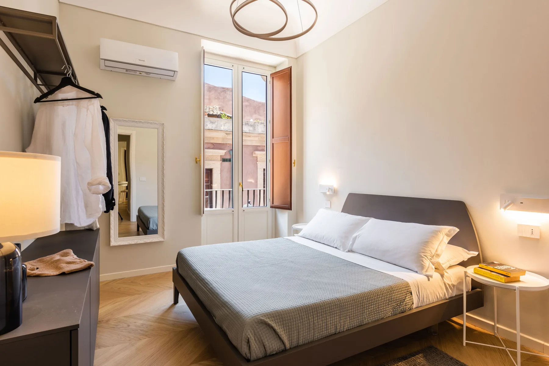 Un dormitorio con una cama bien tendida y una ventana alta.