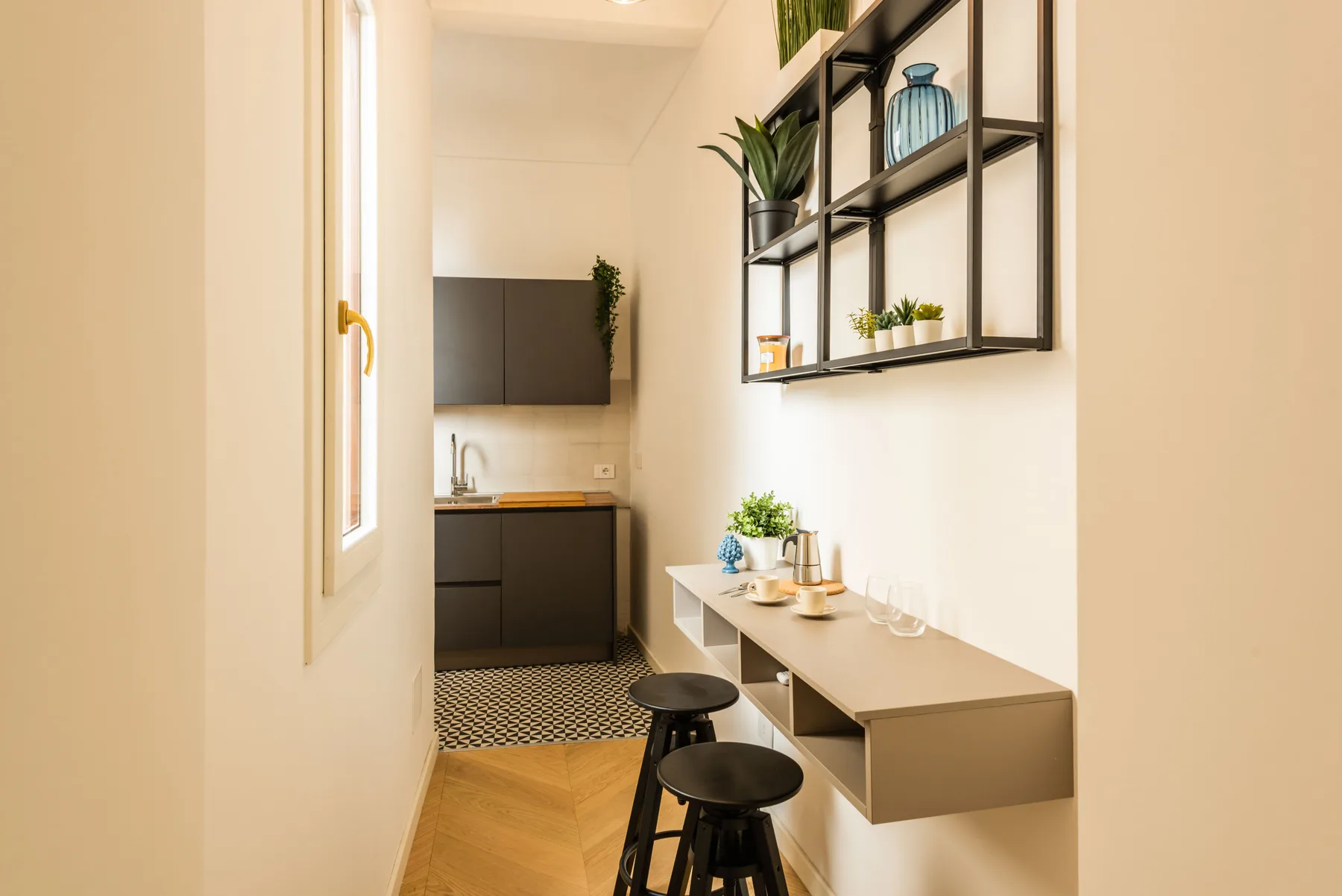 Un pequeño comedor con una mesa montada en la pared, taburetes y estantes abiertos.