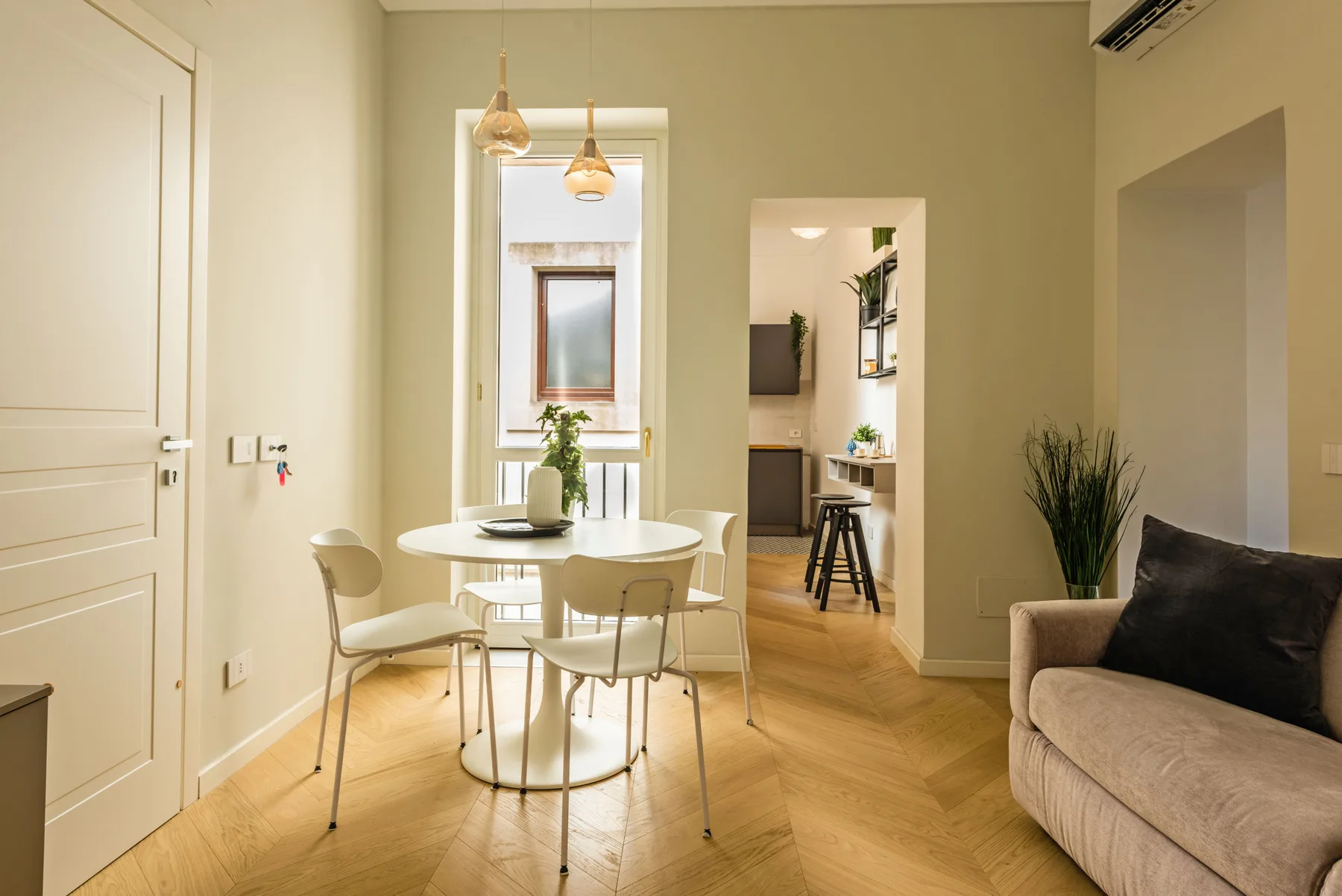 Un comedor luminoso con una mesa redonda y asientos junto a una sala de estar.