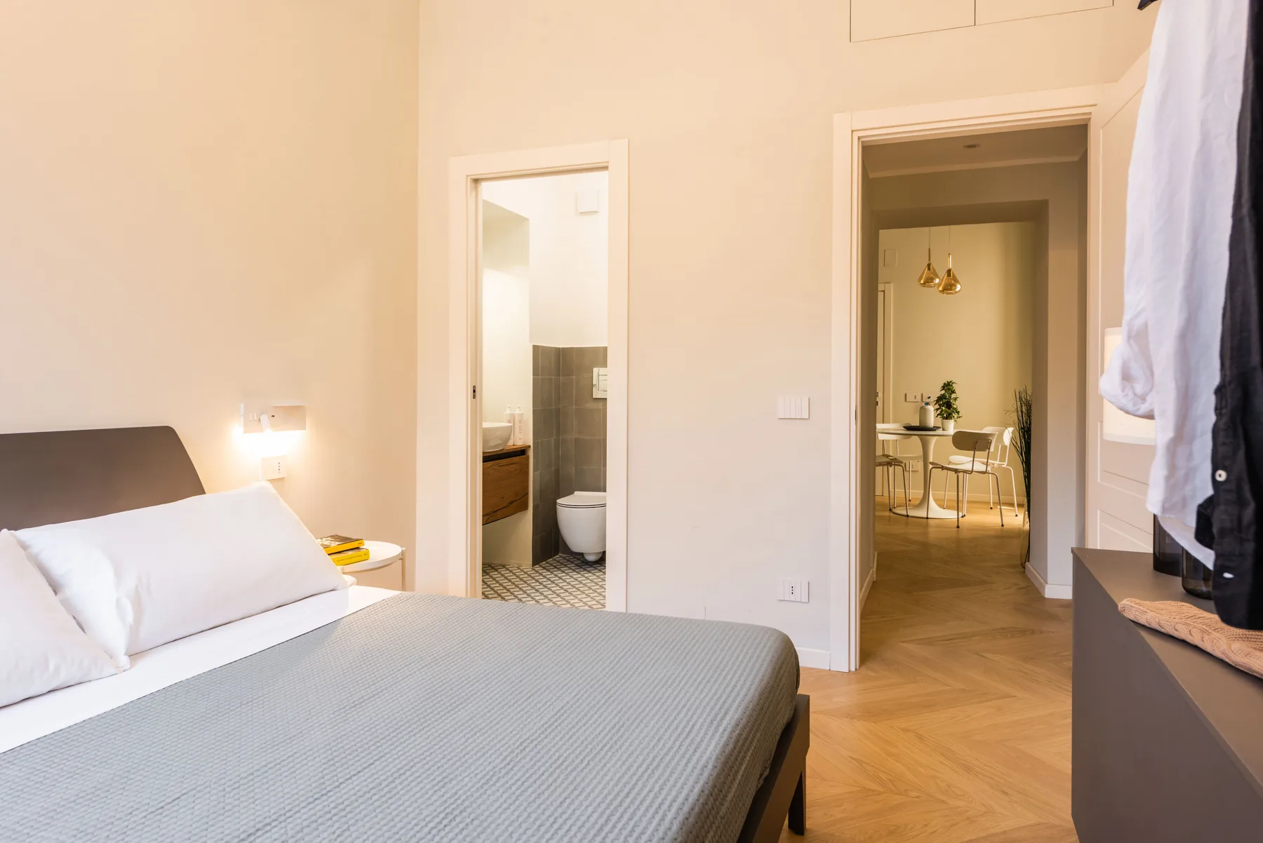 Un dormitorio con una cama y puertas abiertas hacia un baño y un comedor.