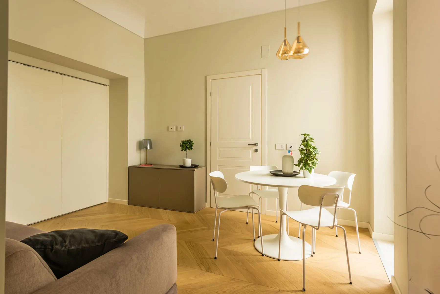Una luminosa zona de comedor con una mesa redonda y asientos junto a una sala de estar.
