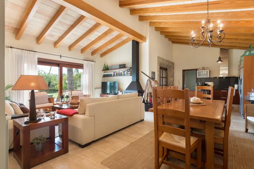 A bright open-plan living and dining room with exposed ceiling beams.