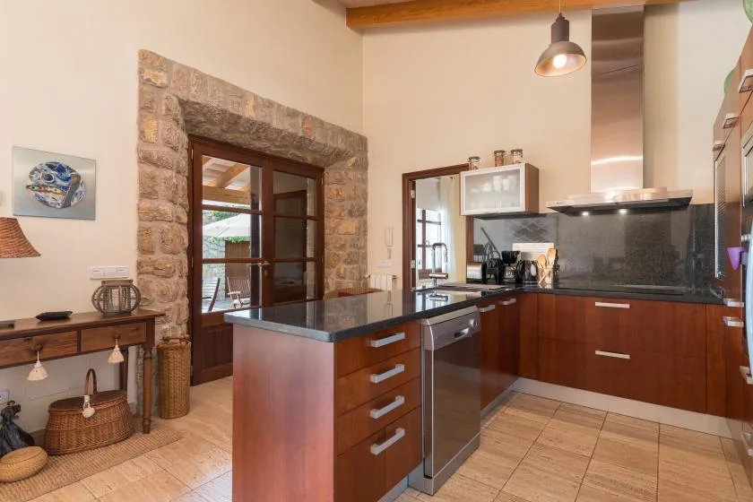 A kitchen with dark countertops, wooden cabinetry, and a central island.