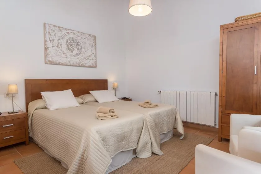 A bedroom with a double bed, bedside tables, and a wooden wardrobe.