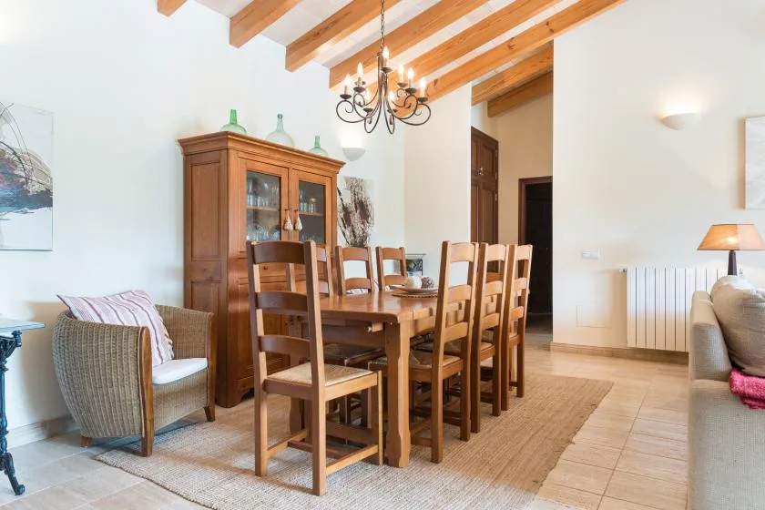 A dining area with a wooden table and chairs beneath exposed ceiling beams.