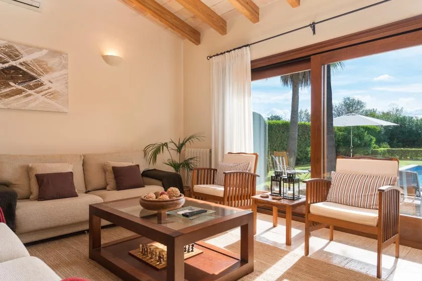 A living room with seating around a wooden coffee table beside large glass doors.