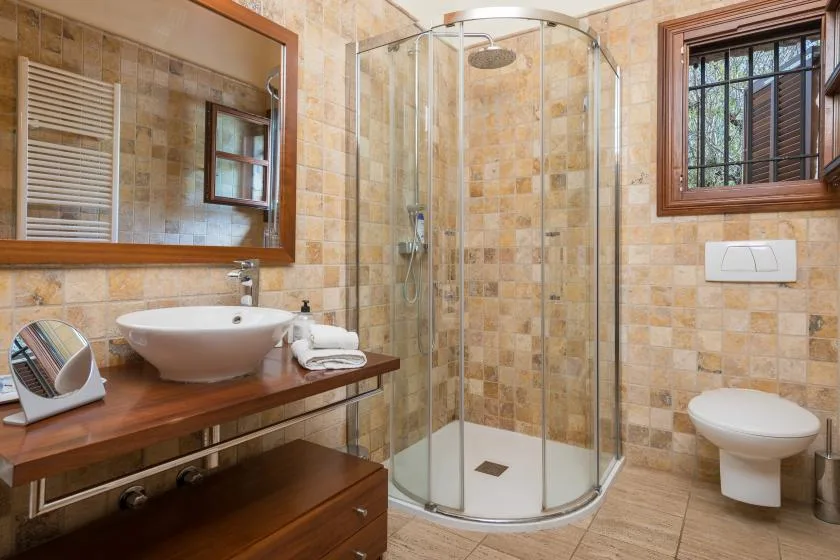A tiled bathroom with a glass shower, sink, and toilet.