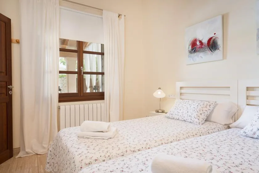 A bedroom with patterned bedding, white curtains, and a window.