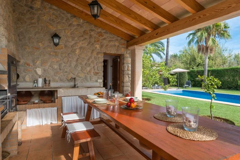 A covered outdoor dining area overlooks a swimming pool and garden.