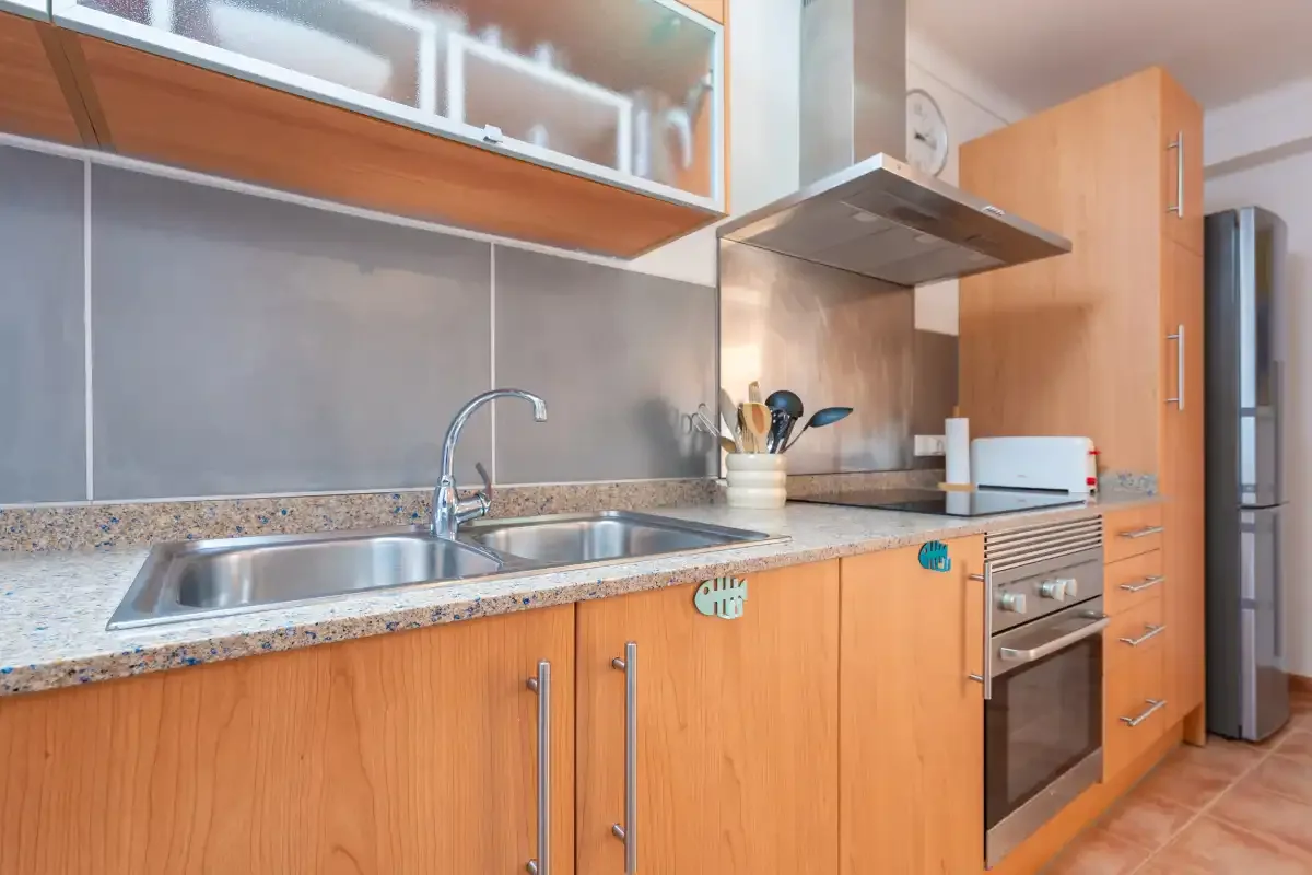 Una cocina con fregadero, encimera y horno integrado.