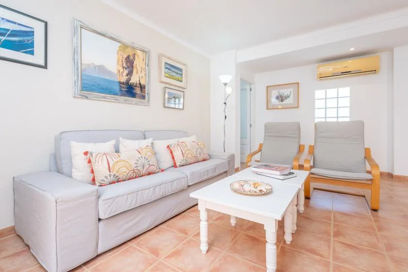 Una sala luminosa con un sofá, dos sillones y una mesa de centro.
