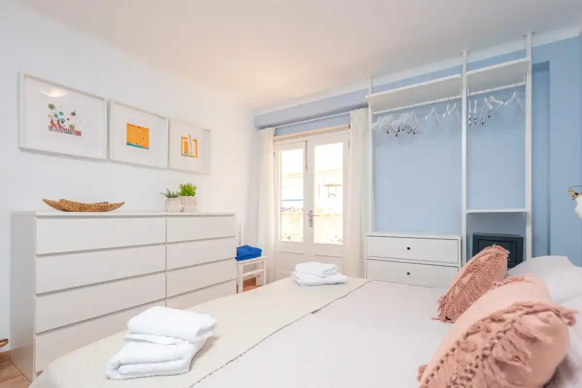 Un dormitorio luminoso con una cama bien hecha y un armario empotrado.