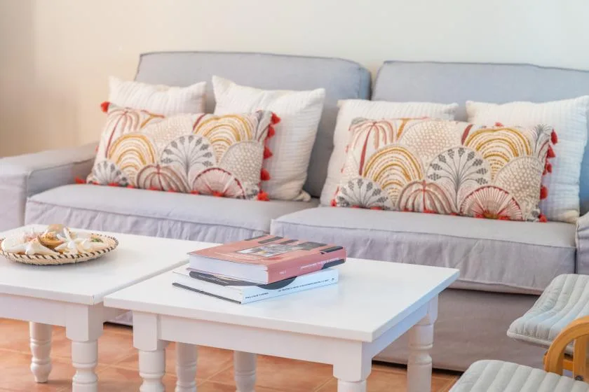 Una sala de estar con un sofá, cojines estampados y una mesa de centro blanca.