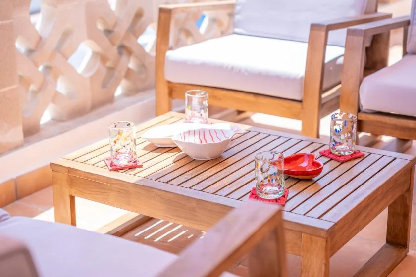 Una zona de estar con asientos de madera y una mesa baja de listones.