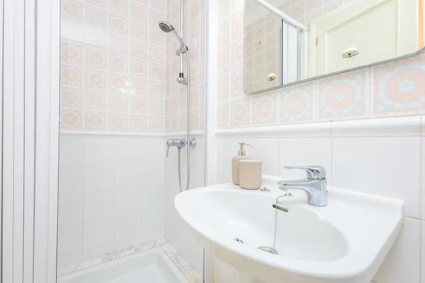 Un baño con azulejos, lavabo, espejo y ducha.