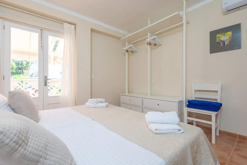 Un dormitorio luminoso con una cama, barras para ropa y una ventana.