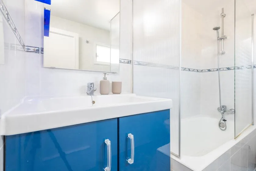 Un baño luminoso con un lavabo y una zona de ducha.