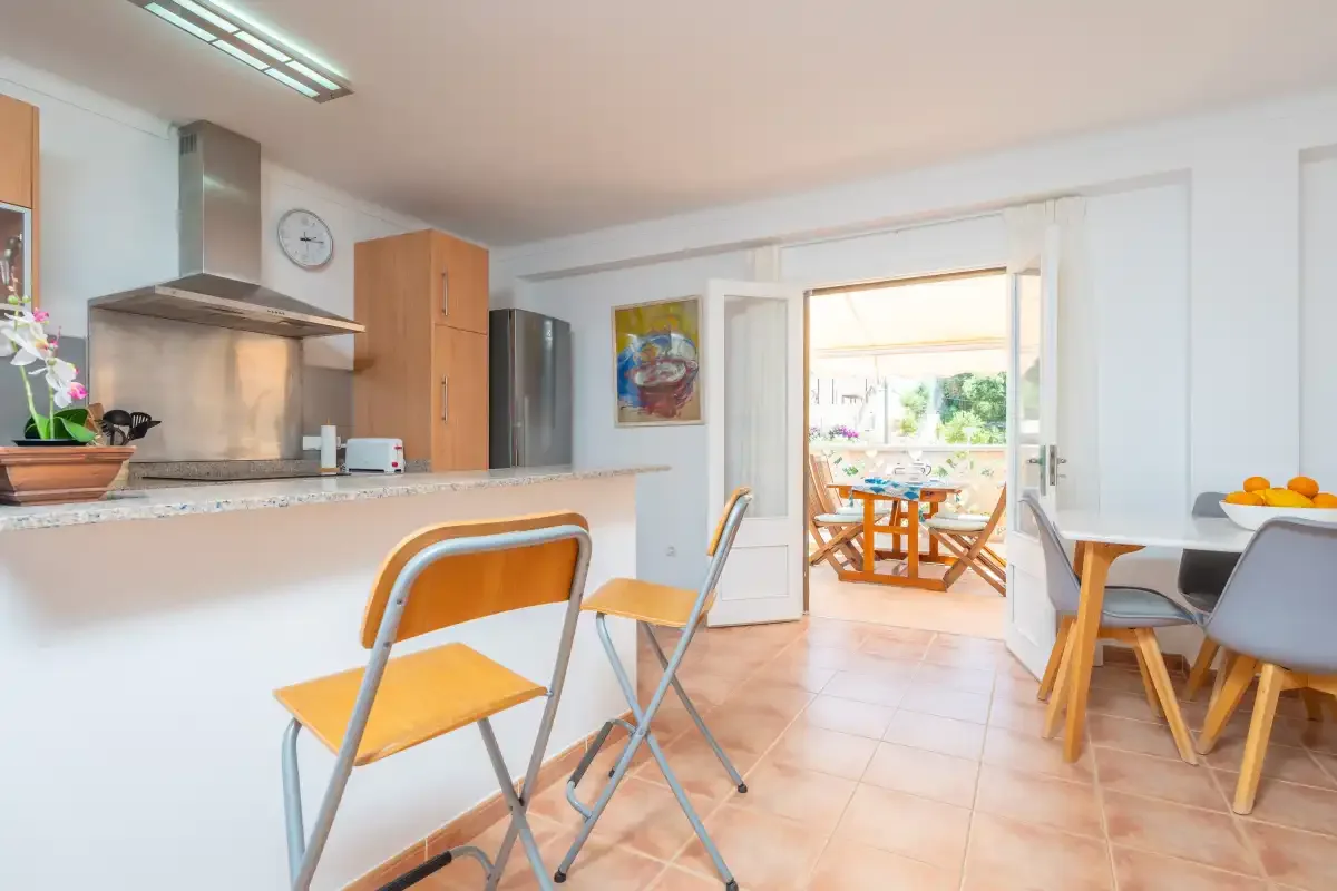 Una luminosa cocina y comedor se abre a una terraza amueblada.