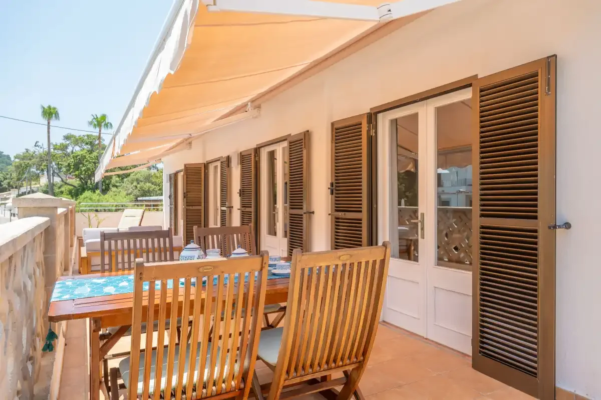 Una terraza exterior con asientos de madera y un toldo retráctil.