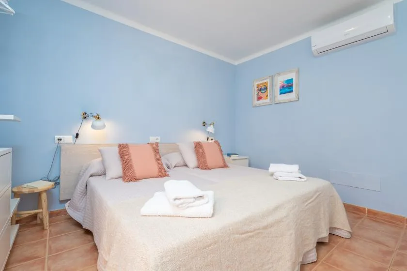 Un dormitorio con una cama doble, paredes azul claro y cuadros enmarcados.