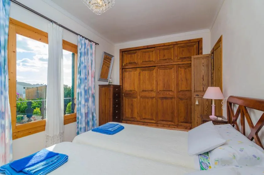 Un dormitorio con una cama, un armario de madera y ventanas con vistas a la vegetación.